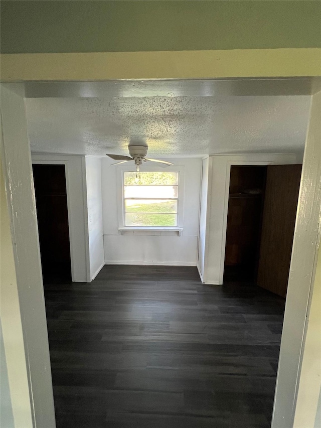 interior space with a textured ceiling, baseboards, and dark wood-type flooring