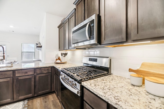 247 Carolina Trce, Fate, TX 75189 - kitchen featuring stainless steel appliances, dark brown cabinets, decorative backsplash, dark wood-style flooring, and light stone counters