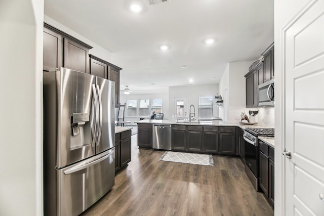 kitchen with dark wood-style flooring, stainless steel appliances, dark brown cabinets, and a peninsula