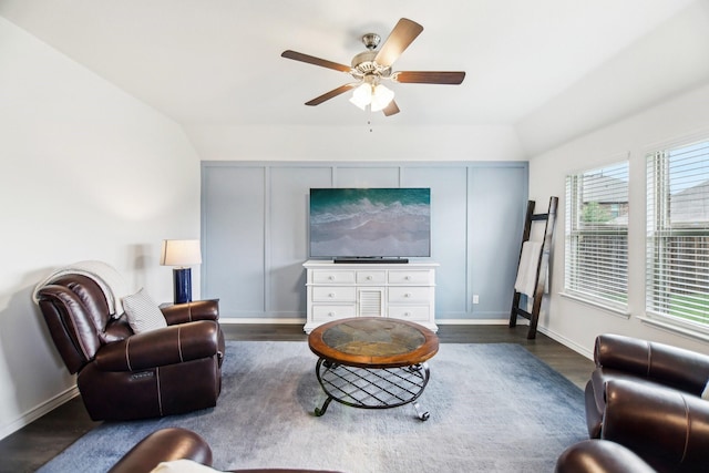 living area with baseboards, ceiling fan, vaulted ceiling, and dark wood-type flooring
