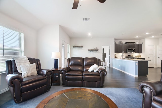 living area with plenty of natural light, a ceiling fan, dark wood finished floors, and visible vents