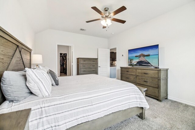 bedroom featuring a walk in closet, ceiling fan, light colored carpet, visible vents, and baseboards