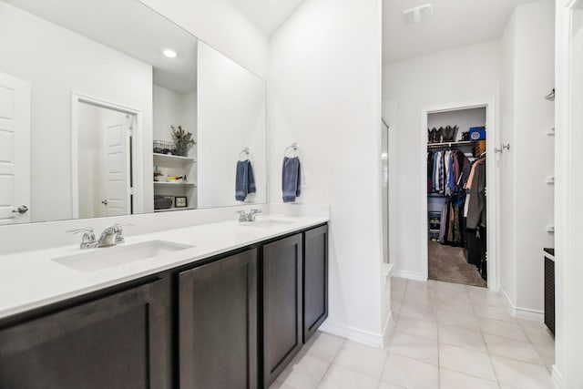 bathroom featuring double vanity, a sink, tile patterned flooring, and a spacious closet