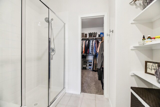 full bath featuring tile patterned flooring, baseboards, a stall shower, and a spacious closet