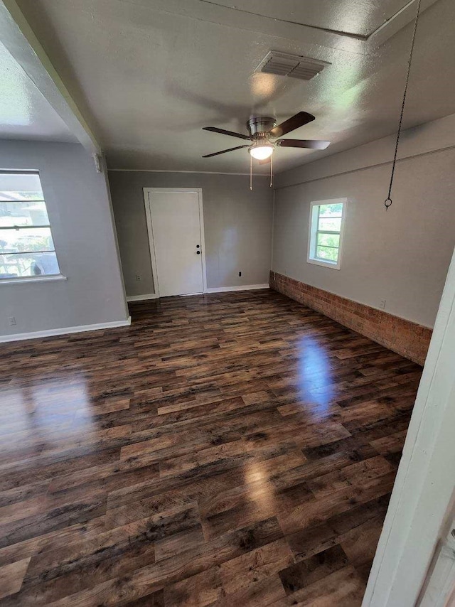 spare room with baseboards, visible vents, ceiling fan, and dark wood-style flooring