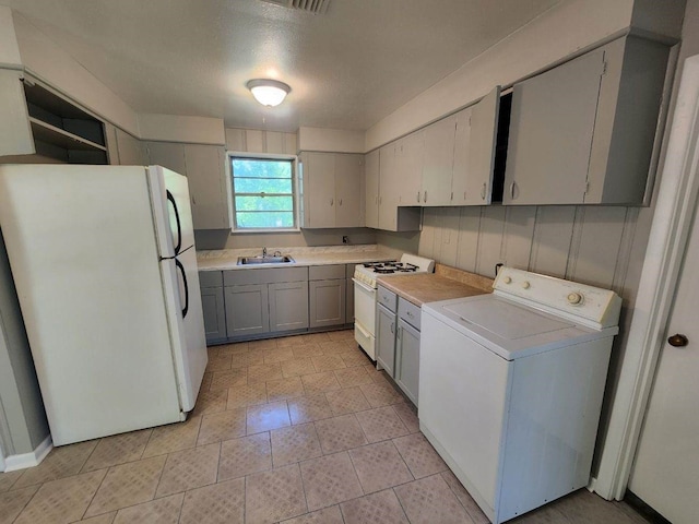 kitchen featuring washer / dryer, white appliances, light countertops, and a sink