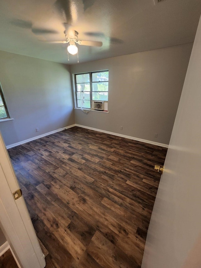 empty room featuring ceiling fan, cooling unit, dark wood-style floors, and baseboards