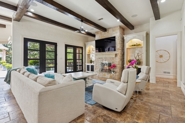 living area featuring beam ceiling, stone tile floors, and visible vents