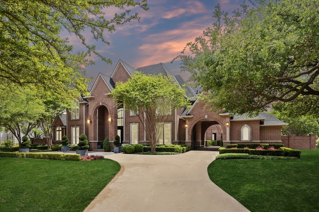view of front of home featuring a front lawn, curved driveway, and brick siding
