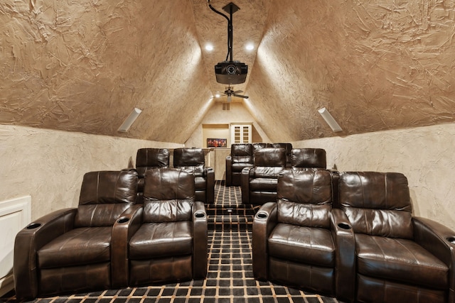 cinema room with lofted ceiling and a textured wall