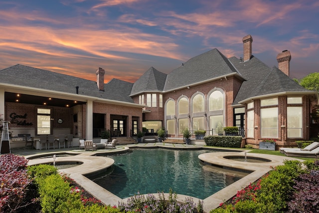 outdoor pool with a patio, an outdoor bar, and an in ground hot tub