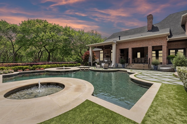 outdoor pool with an in ground hot tub and a patio area