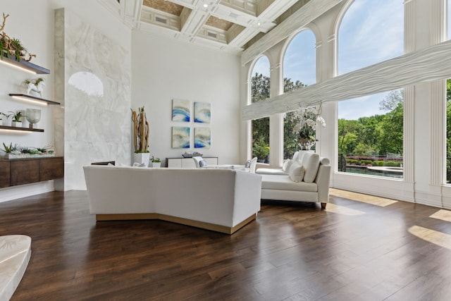 living room with dark wood-style flooring, beam ceiling, coffered ceiling, ornamental molding, and a towering ceiling