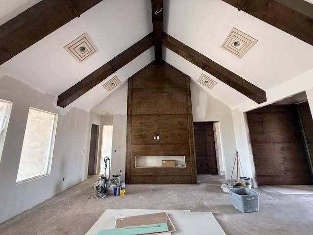 unfurnished living room featuring high vaulted ceiling, visible vents, and beam ceiling