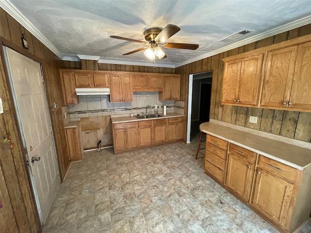 kitchen featuring a sink, visible vents, under cabinet range hood, a ceiling fan, and brown cabinetry