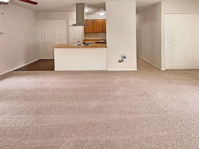 unfurnished living room featuring a ceiling fan, baseboards, a sink, and dark colored carpet