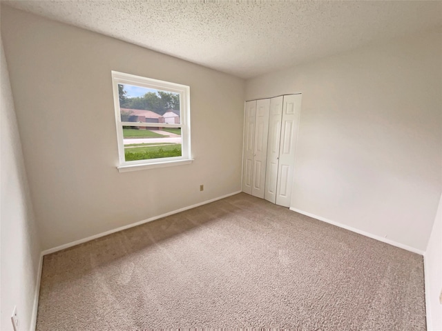 unfurnished bedroom with a closet, baseboards, carpet flooring, and a textured ceiling