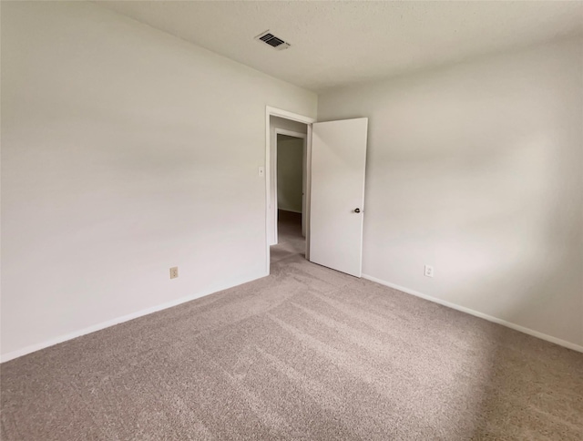 empty room with light colored carpet, baseboards, and visible vents