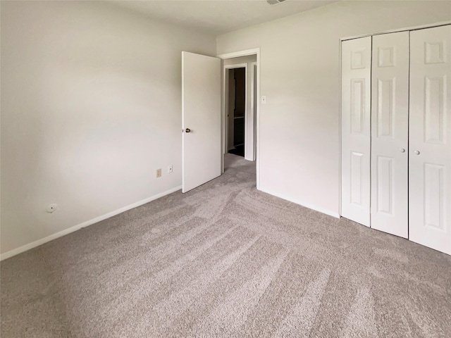unfurnished bedroom with baseboards, light carpet, and a closet