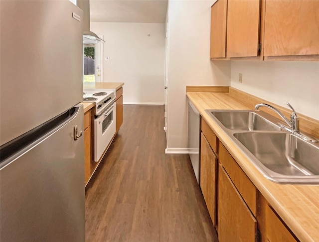 kitchen featuring appliances with stainless steel finishes, a sink, light countertops, baseboards, and dark wood-type flooring