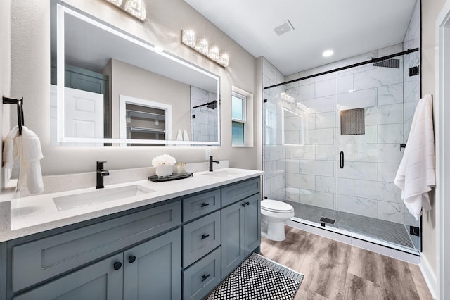 bathroom featuring a stall shower, a sink, wood finished floors, and visible vents