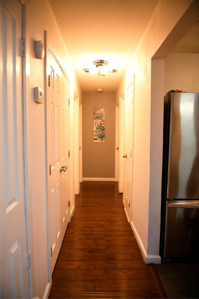 hallway with baseboards and dark wood-type flooring