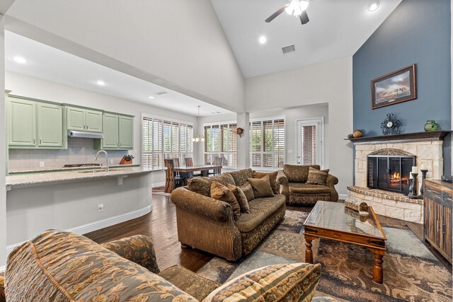 living area featuring visible vents, a fireplace, baseboards, ceiling fan, and dark wood-style floors