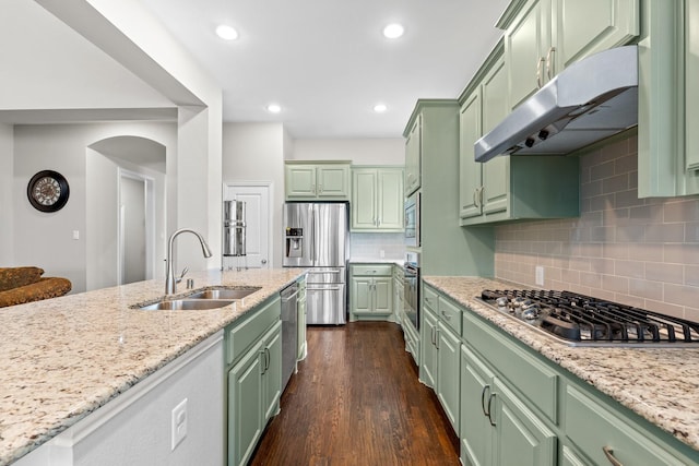 kitchen featuring appliances with stainless steel finishes, a sink, light stone counters, green cabinets, and under cabinet range hood