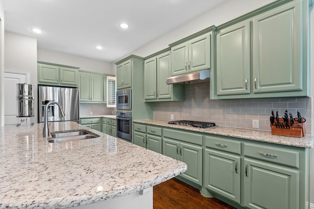 kitchen featuring stainless steel appliances, green cabinetry, a sink, and tasteful backsplash