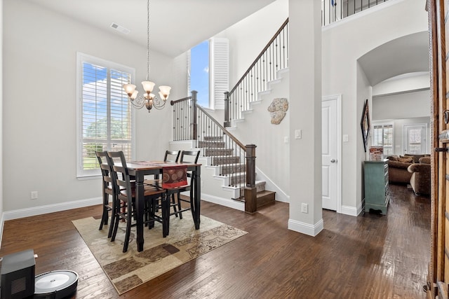 dining space with arched walkways, dark wood-type flooring, stairs, and visible vents