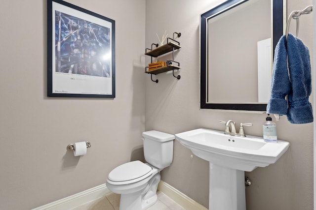 half bath with baseboards, tile patterned flooring, and toilet