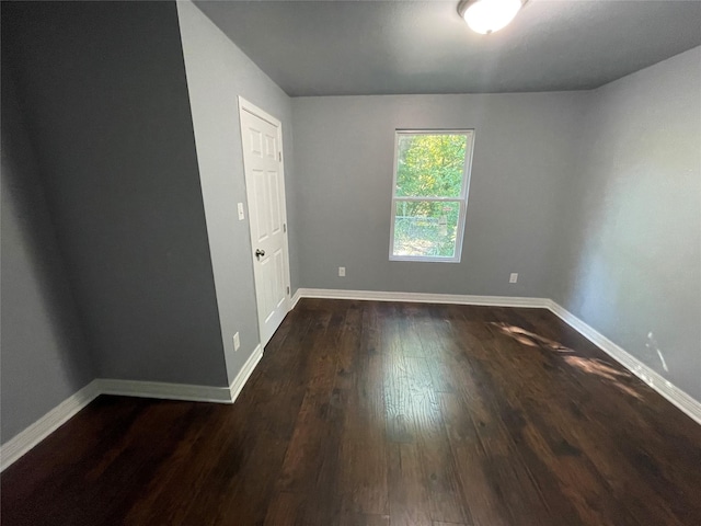 spare room with dark wood finished floors and baseboards