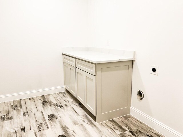 clothes washing area featuring laundry area, light wood-style flooring, baseboards, and electric dryer hookup