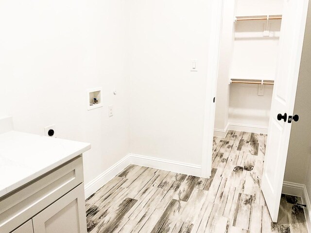 laundry room with cabinet space, washer hookup, baseboards, electric dryer hookup, and light wood-type flooring