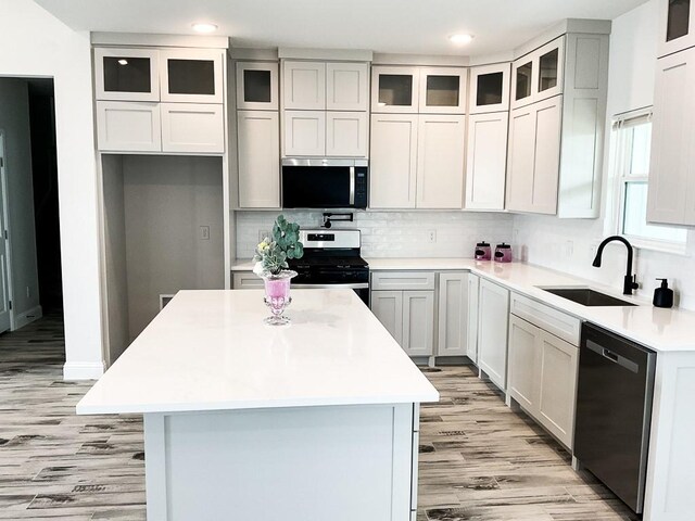kitchen with light wood-type flooring, a sink, appliances with stainless steel finishes, and a kitchen island