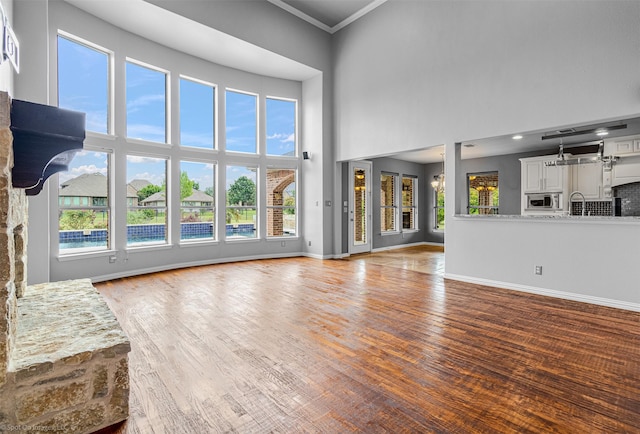 794 Amherst Dr, Rockwall, TX 75087 - unfurnished living room with baseboards, ornamental molding, a towering ceiling, wood finished floors, and a sink
