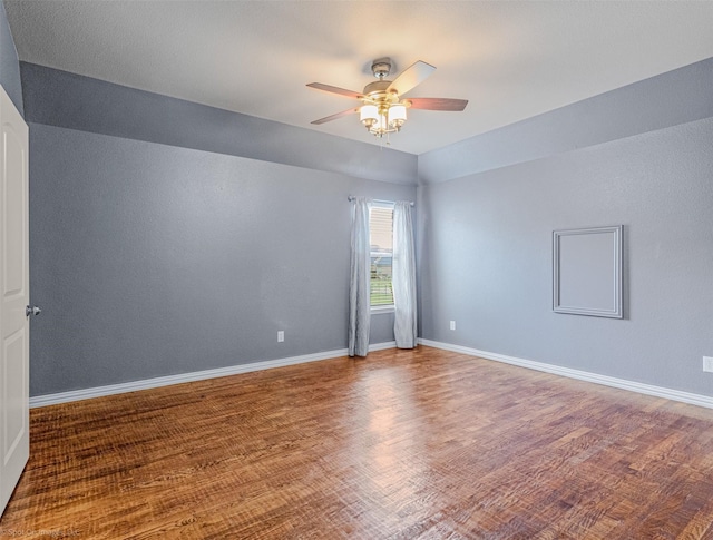 spare room with baseboards, ceiling fan, and wood finished floors