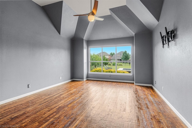 spare room with vaulted ceiling, wood finished floors, baseboards, and ceiling fan