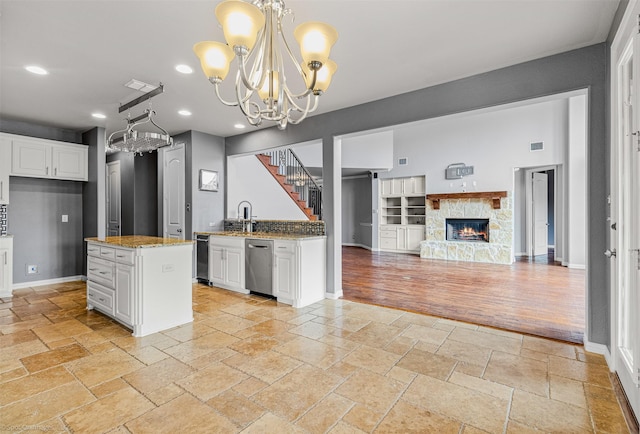 kitchen featuring a notable chandelier, recessed lighting, stone tile flooring, dishwasher, and white cabinetry
