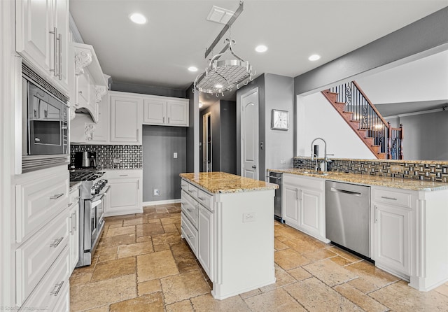 kitchen featuring recessed lighting, stainless steel appliances, a sink, and stone tile flooring