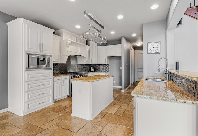 kitchen featuring backsplash, stone tile floors, appliances with stainless steel finishes, and a sink