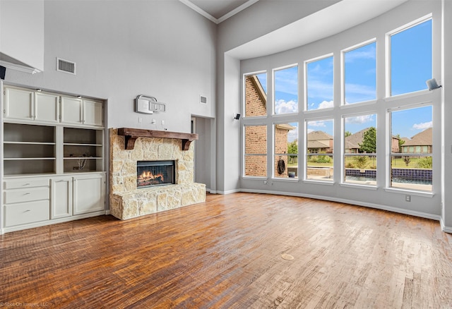 unfurnished living room featuring crown molding, a towering ceiling, baseboards, and visible vents