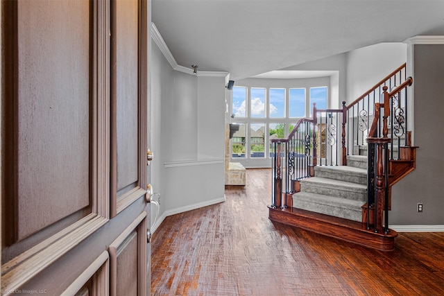 entrance foyer with ornamental molding, stairs, baseboards, and wood finished floors
