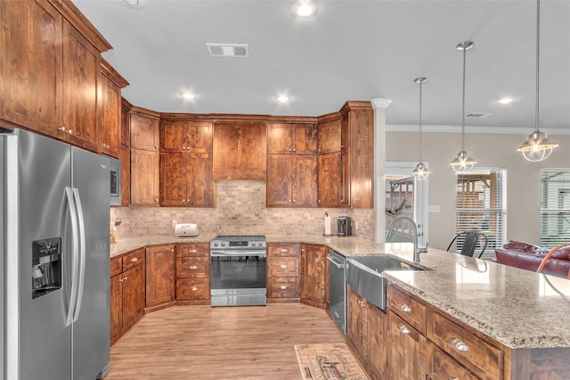 kitchen featuring a sink, stainless steel appliances, tasteful backsplash, light wood-type flooring, and a peninsula