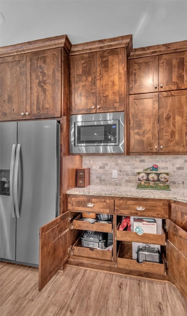 kitchen featuring tasteful backsplash, appliances with stainless steel finishes, and light wood finished floors
