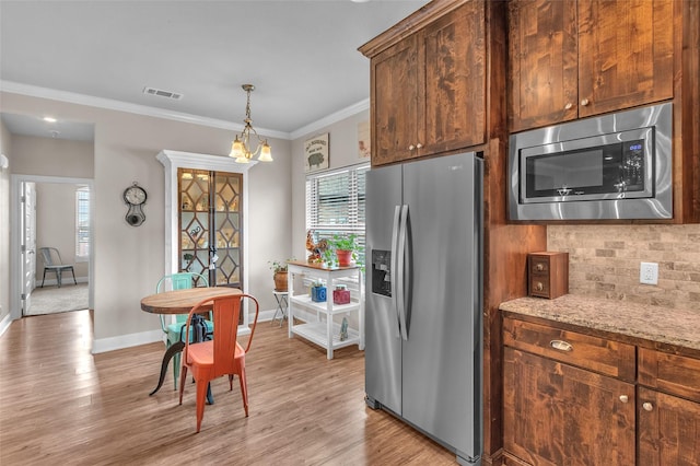 kitchen featuring visible vents, stainless steel appliances, light wood-type flooring, and backsplash