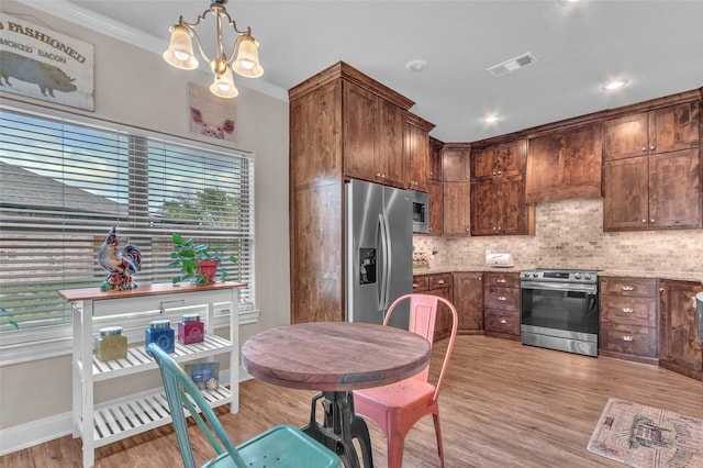 kitchen with stainless steel appliances, light wood-type flooring, backsplash, visible vents, and a notable chandelier