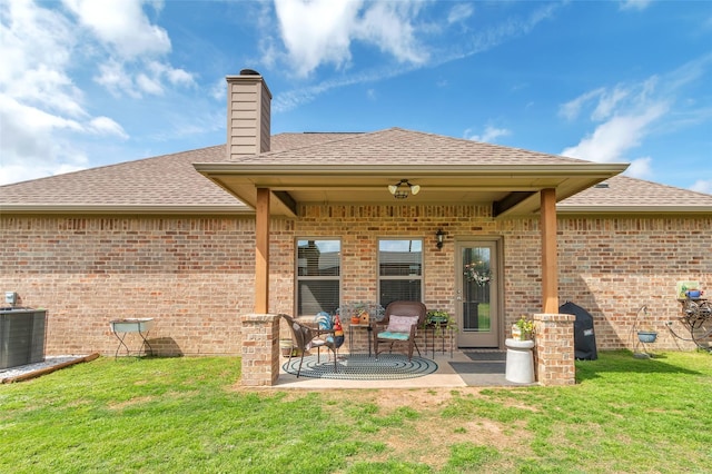 rear view of property featuring central AC unit, a yard, a shingled roof, and brick siding