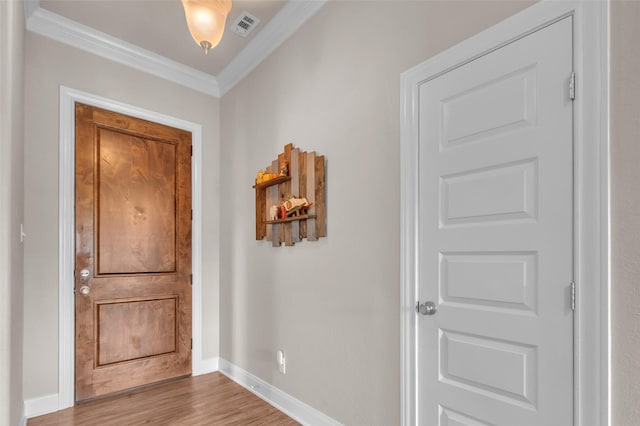 foyer entrance featuring wood finished floors, visible vents, crown molding, and baseboards