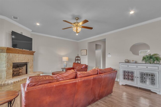 living area featuring visible vents, ceiling fan, ornamental molding, a fireplace, and wood finished floors